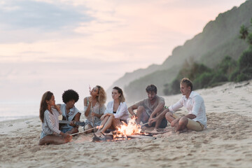 Friends sitting by the fire on the beach