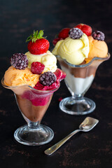 Ice cream in glass bowl. Ice creams on dark background. Milk, chocolate, cherry, melon and caramel ice cream.