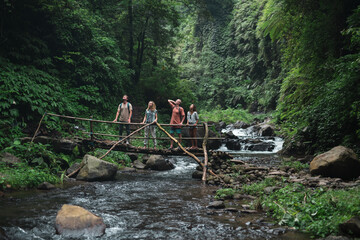 tourists stand on the bridge over the river in the jungle