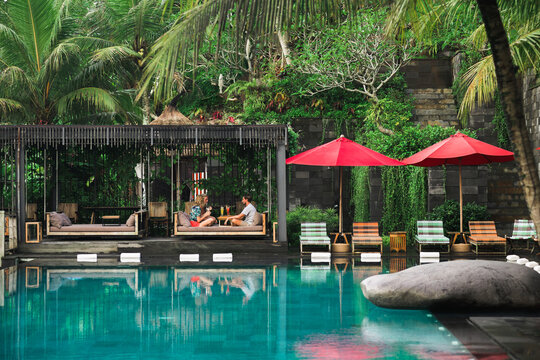 couple of tourists relaxing by the pool in a resort in the tropics
