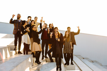 Happy colleagues with alcoholic beverages on stairs during party outdoors