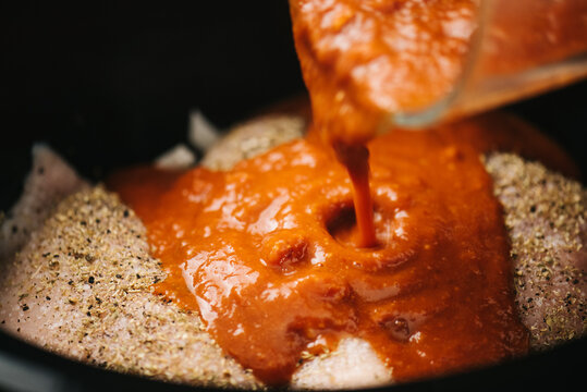 Pouring tinga sauce over chicken breasts