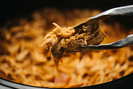 Tongs with shredded chicken tinga meat
