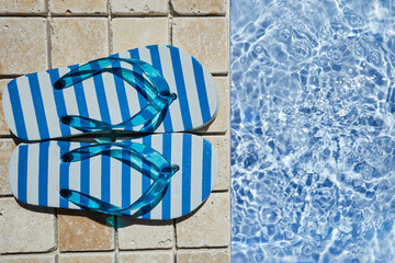 Summer vacation. Flip flops on the travertine stone by swimming pool. Blue sea surface with waves, texture water.