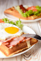 Waffle wholesome breakfast. Sour waffles with grilled sausages, fried eggs, delicious sauce and fresh vegetables.