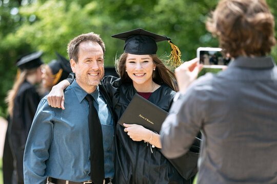 Grad: Parent And Child Pose For Photograph With Diploma