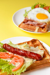 Waffle wholesome breakfast. Sour waffles with grilled sausages, fried eggs, delicious sauce and fresh vegetables.