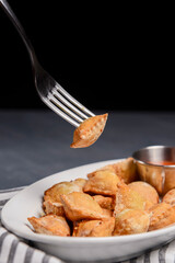 Fried dumplings stuffed with meat and served with tomato sauce on a white plate.