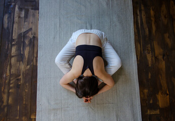 Top view young sporty woman hatha yoga instructor keep fit do gymnastics practice training bound angle posture seated Baddha Konasana pose on gym mat in wooden floor. Healthy lifestyle concept.