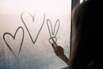 Young woman drawing hearts on the window
