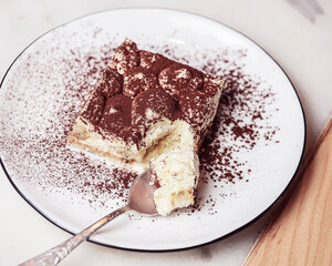 Traditional Tiramisu Cake served on a white plate over wooden background. Italian French cuisine concept