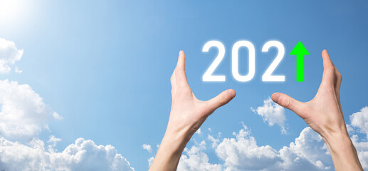 Hand hold 2021 positive icon on sky background.Plan business positive growth in year 2021 concept. Businessman plan and increase of positive indicators in his business, Growing up business concepts.