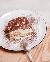 Traditional Tiramisu Cake served on a white plate over wooden background. Italian French cuisine concept