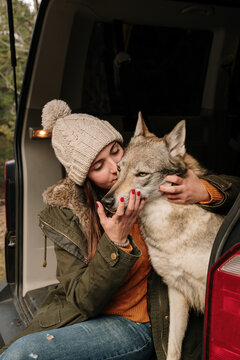 Young woman in camper van petting a cute  wolf dog in the mountain