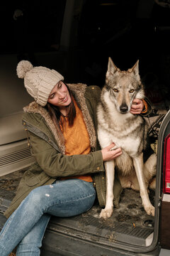 Young woman in camper van petting a cute  wolf dog in the mountain