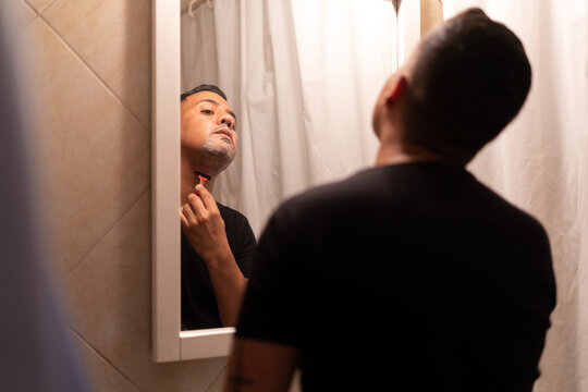 hispanic latino man shaving himself in the bathroom