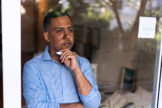 Latin hispanic man working at home and writting graphs on glass wall