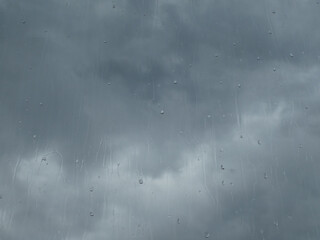 Window glass in a rainy day. Raindrops on window with cloudy sky background