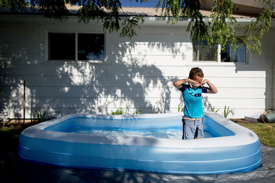 Boy wipes eyes in backyard pool