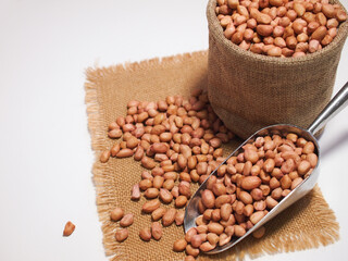 Dried peanuts in scoop with sack bag on a white background.
