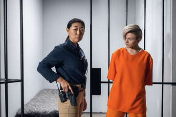 Blonde inmate in an asian women's general security prison is led out of her cell by a uniformed guard, with a holstered pistol and a walkie-talkie.