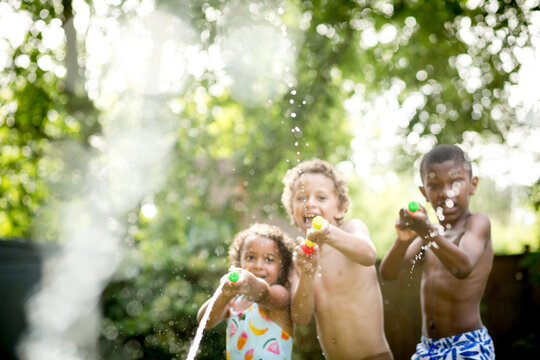 Soft focus sibilings spray water drops at viewer