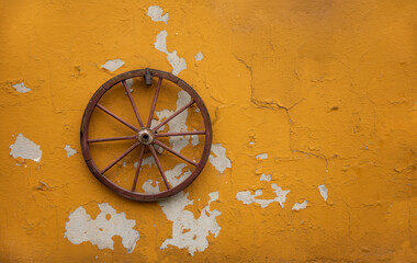 Fototapeta na wymiar old wagon wheel on the yellow wall
