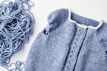 blue knitted product on knitting needles on a white background