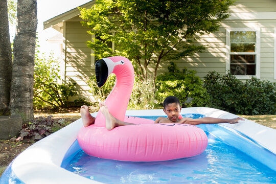 Boy floats on flamingo in backyard pool