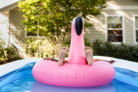 Feet of child floating on flamingo in pool