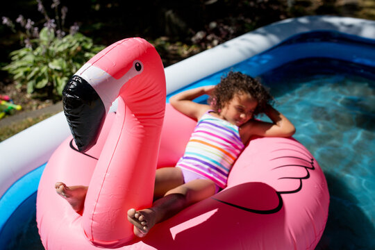 Girl floats on flamingo in backyard pool