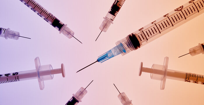 Grouping of Medical Syringes on Blue-Orange Background 