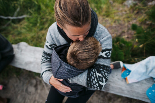 Mom and boy cuddling outside on log bench