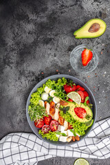 Ketogenic diet food, chicken fillet, quinoa, avocado, avocado, feta cheese, quail eggs, strawberries, nuts and lettuce. healthy meal concept, vertical image. top view. place for text
