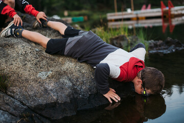 Boy looking in lake water with goggles