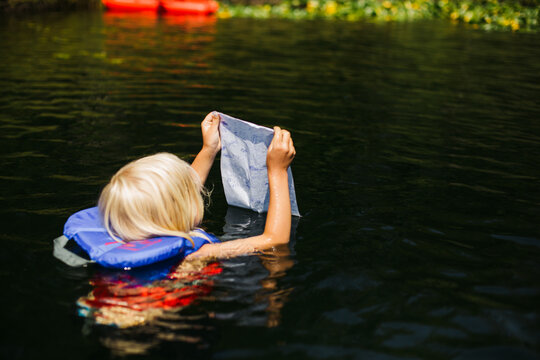 Kid Swiming With Lifejacket And Map In Lake