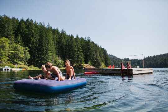 Kids playing on air matress floaty on lake in summer.