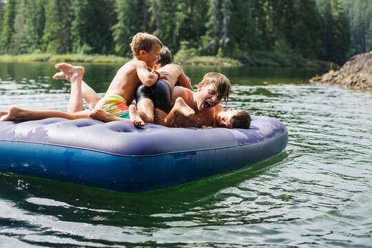Kids playing on air matress floaty on lake in summer.