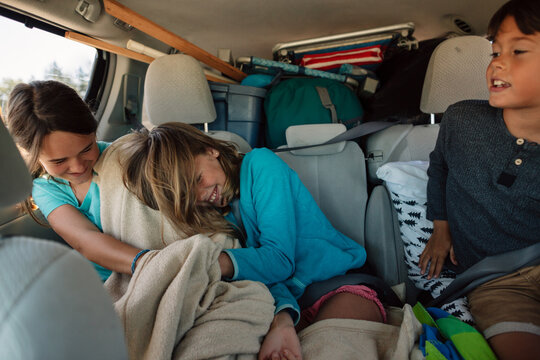 Kids tickling and goofing around in the back of car on camping r