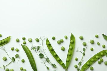 Green pea pods, seeds and twigs on white background