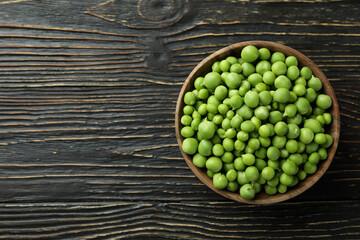 Bowl with pea seeds on wooden background