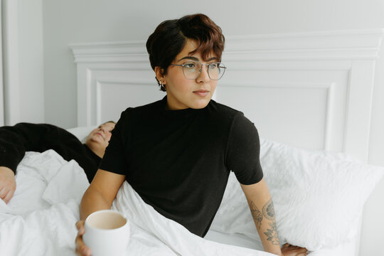 Non Binary person drinking coffee in bed