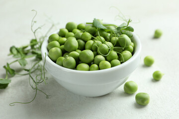 Bowl with pea seeds on white textured background