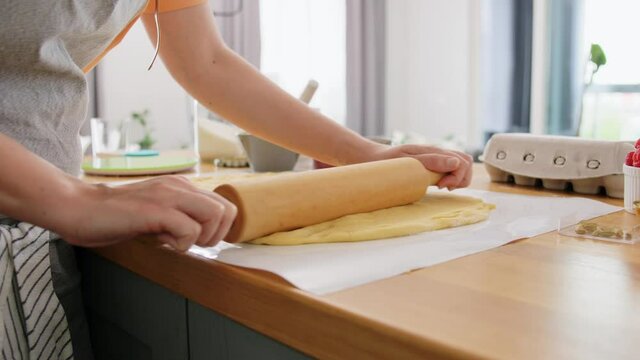 culinary, bake and people concept - young woman cooking food on kitchen at home and rolls dough with rolling pin