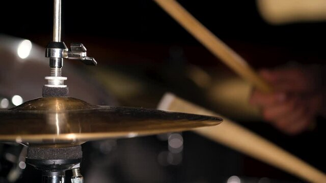 Hands of musician drummer holding drum sticks hitting on hi-hat cymbal