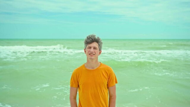 portrait happy relaxed man in enjoying sea beach getaway vacation, feeling good at windy day on coast with waves