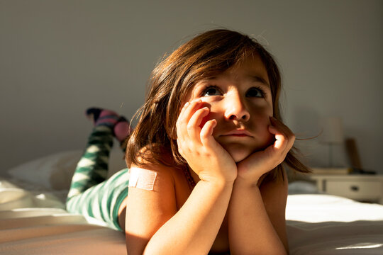 Little girl with a band aid in her shoulder laying in bed