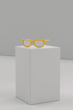 Yellow sunglasses on grey parallelepiped