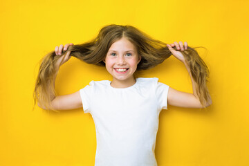 When my hair is long I go to hairdresser. Happy child hold long hair. Smiling teen girl on yellow background. Trendy long hairstyle. Long hair growth stimulant. Natural hair extensions. Salon haircare