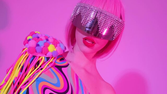 Portrait of a girl in creative glasses in pink trendy neon light. The woman dances and moves gracefully to the club music.